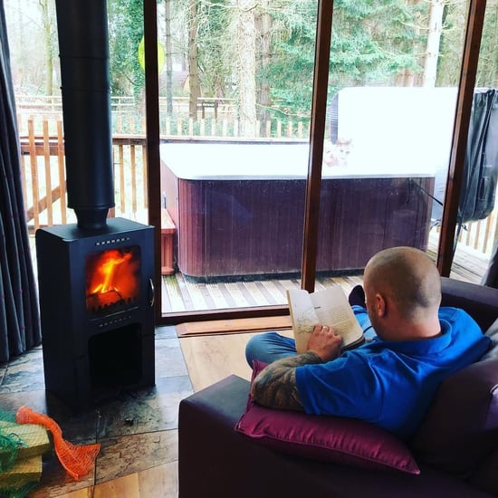 Man sat reading in front of the log burner at Forest Holidays