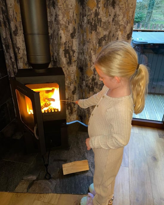 Girl toasting marshmallows on the log burner at Forest Holidays