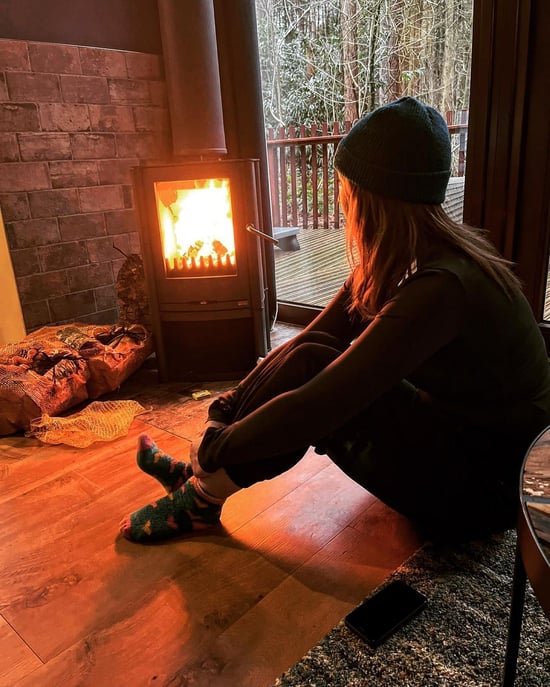 Woman sat in front of the log burner at Forest Holidays