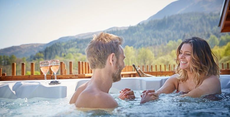 Couple sitting in the hot tub in a Golden Oak Hideaway at Forest Holidays 