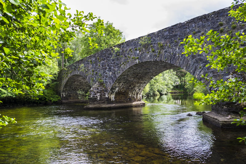 The arches of the stone hump back bridge over the River Balvag at Balquhidder, Scotland.