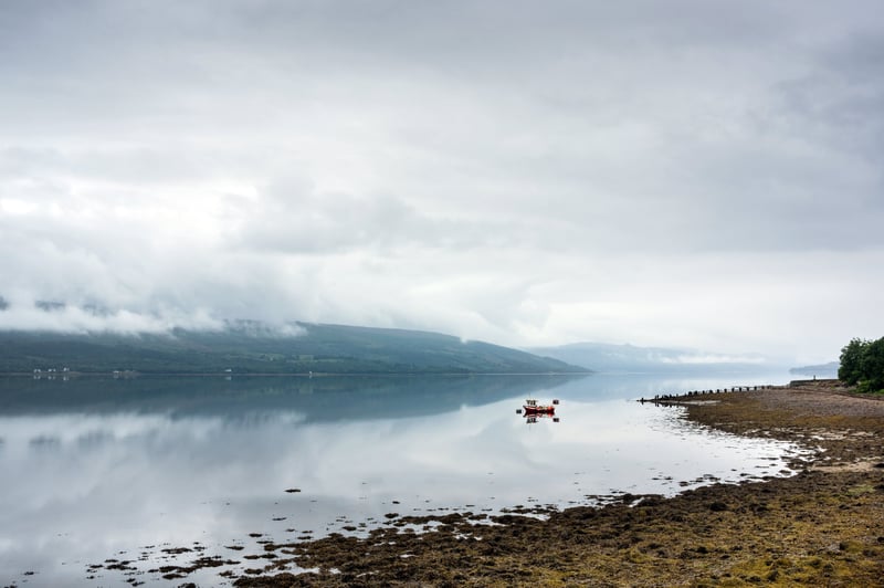 A small boat sitting on Loch Goil on a calm misty afternoon.