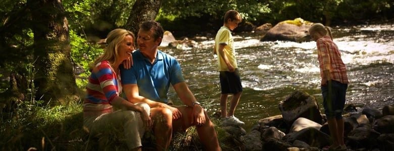 A family relax by a stream in the forest