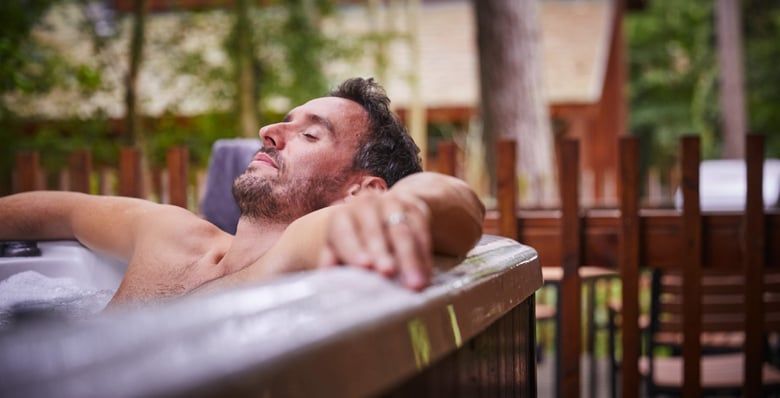 Man relaxing in a hot tub at Forest Holidays