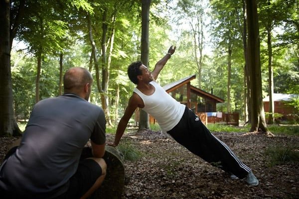 Two men exercising in the forest at Forest Holidays
