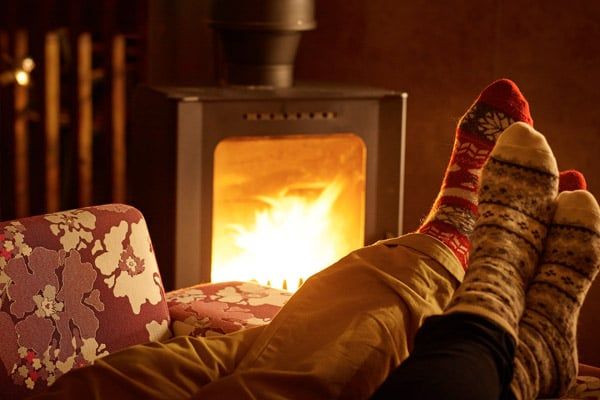 Feet resting in front of a log burner at Forest Holidays 