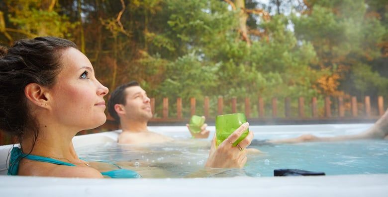 A couple relaxing in their hot tub at Forest Holidays