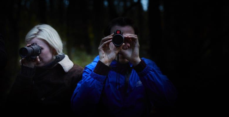 A couple using night vision goggles in the forest