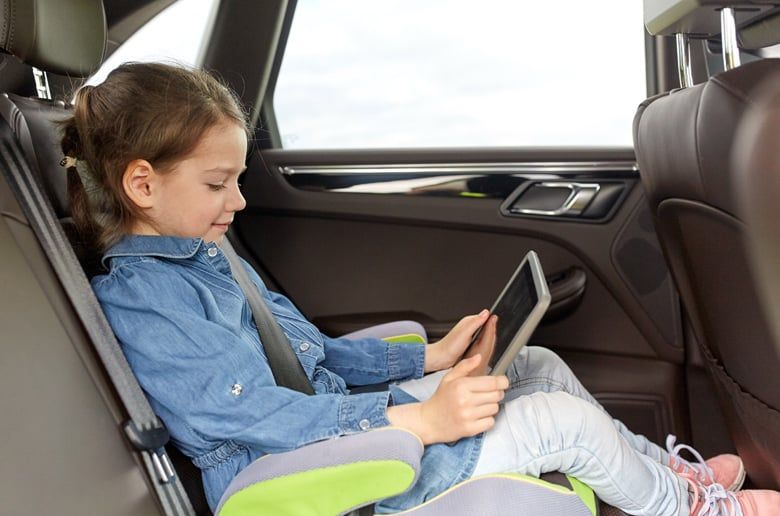 Child sat in a car using an electronic device