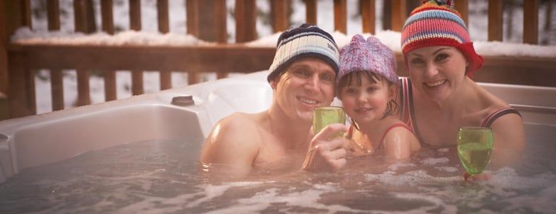 Family in the hot tub wearing hats at Forest Holidays