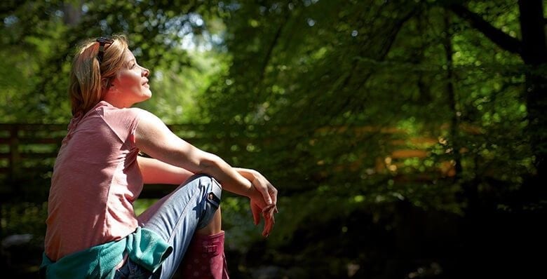 Woman sat in the sunshine in the forest